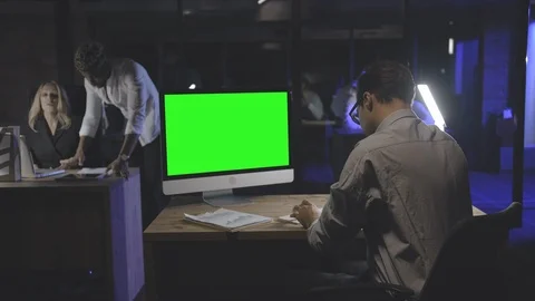 Young employee working on computer with green screen empty monitor. Stock Footage 125688729