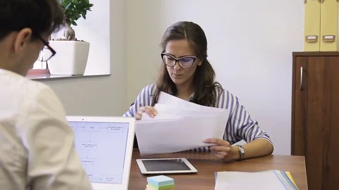 Young employees discuss working papers sitting in company. Stock Footage 82235891