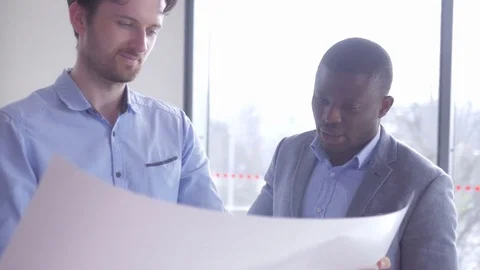 Young employees discussing the data from the large sheet of paper Stock Footage 73865951