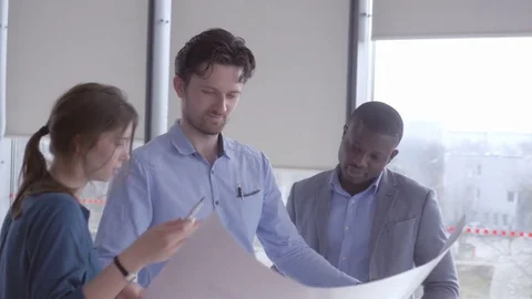 Young employees discussing the data from the large sheet of paper Stock Footage 73867478
