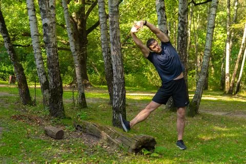 A young enduring athletic athlete is doing stretching in the forest outdoors Stock Photos
