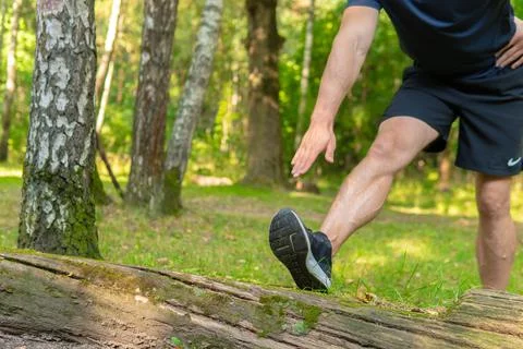 A young enduring athletic athlete is doing stretching in the forest outdoors Foto stock