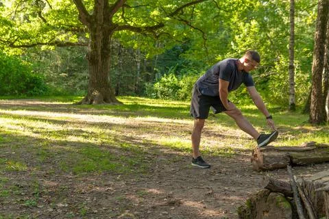 A young enduring athletic athlete is doing stretching in the forest outdoors Stock Photos