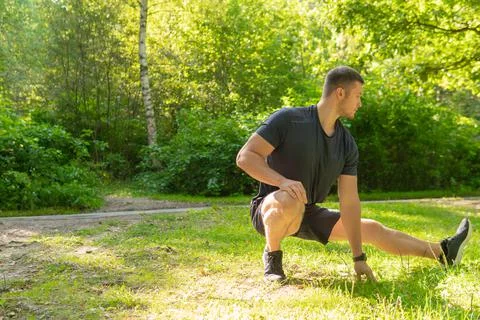 A young enduring athletic athlete is doing stretching in the forest outdoors Foto stock