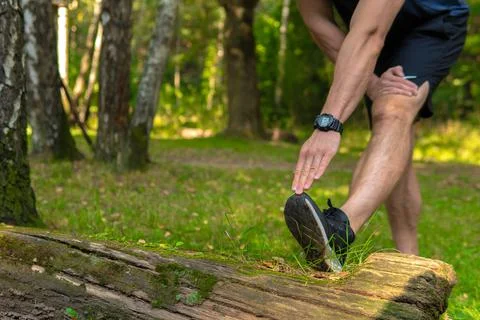 A young enduring athletic athlete is doing stretching in the forest outdoors Foto stock