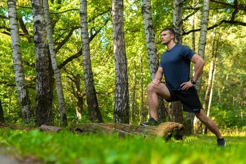 A young enduring athletic athlete is doing stretching in the forest outdoors Stock Photos