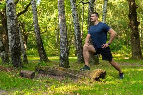 A young enduring athletic athlete is doing stretching in the forest outdoors Stock Photos