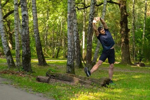 A young enduring athletic athlete is doing stretching in the forest outdoors Foto stock