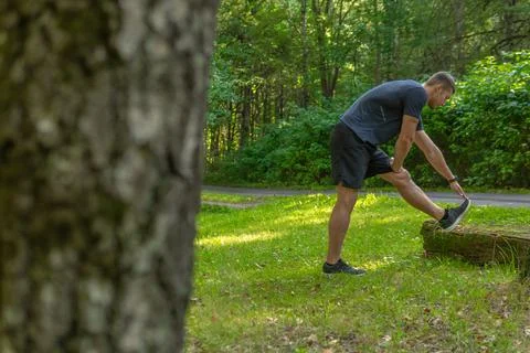 A young enduring athletic athlete is doing stretching in the forest outdoors Stock Photos