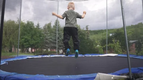 Young energetic boy jumping up and down on a trampoline Stock Footage 337866132