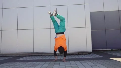 Young energetic guy dancer breakdancing outdoors and walking on hand in the city Stock Footage 293839848
