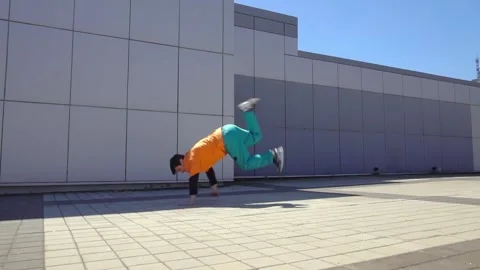 Young energetic guy dancer breakdancing outdoors in the city on the street Stock Footage 293839876