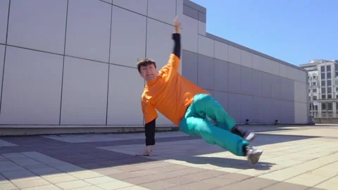 Young energetic guy dancer breakdancing outdoors in the city on the street Stock Footage 293839889
