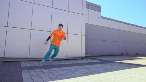 Young energetic guy dancer breakdancing outdoors in the city on the street Stock Footage 293839964