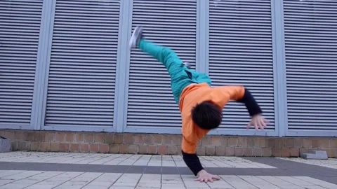 Young energetic guy dancer breakdancing outdoors in the city on the street Stock Footage 293840024