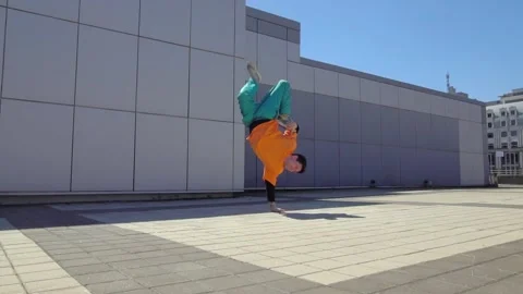 Young energetic guy dancer breakdancing outdoors and jumping on hand in the city Stock Footage 295069146