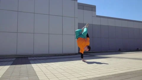 Young energetic guy dancer breaksdancing outdoors in the city on the street Stock Footage 293839856