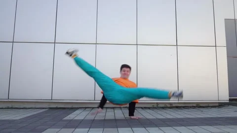 Young energetic guy dancer breaksdancing outdoors in the city on the street Stock Footage 293839958