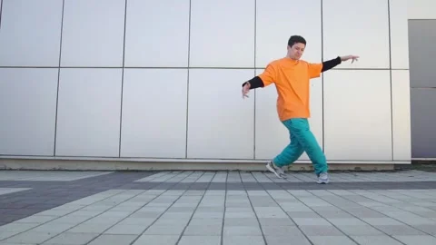 Young energetic guy dancer breaksdancing outdoors in the city on the street Stock Footage 293839987