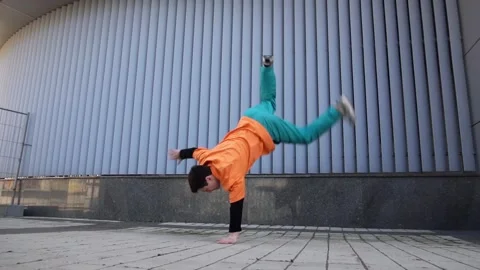 Young energetic guy dancer breaksdancing outdoors in the city on the street Stock Footage 293840008