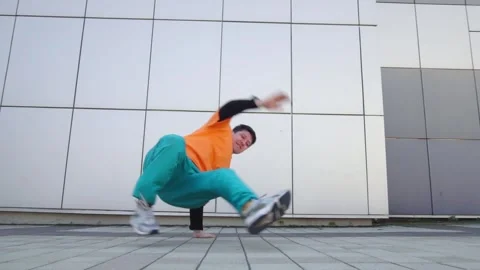 Young energetic guy dancer breaksdancing outdoors in the city on the street Stock Footage 293840012