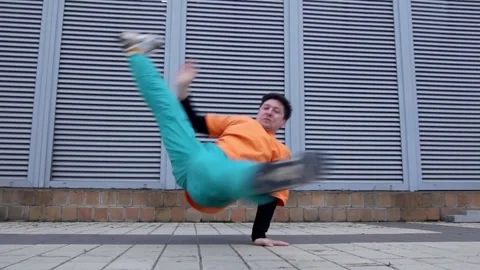 Young energetic guy dancer breaksdancing outdoors in the city on the street Stock Footage 293840029