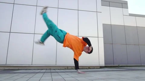 Young energetic guy dancer breaksdancing outdoors in the city on the street Stock Footage 293840035