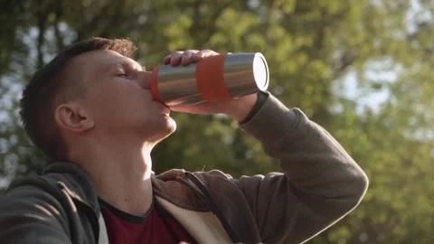 Young energetic man drinking protein shake after workout outdoors in the park. Stock Footage 208876309