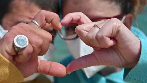 Young engaged couple with mask make the shape  of the heart with their hands Stock Footage 154659607