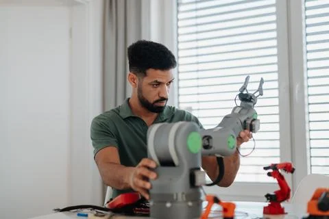 Young engineer building and programming a robotic arm at home. Foto stock