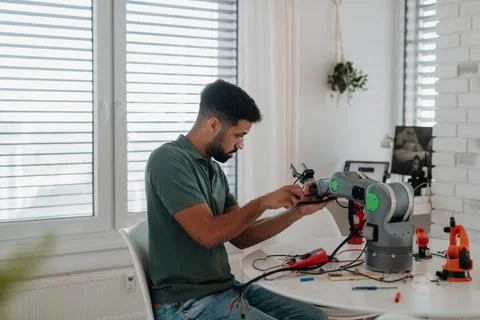 Young engineer building and programming a robotic arm at home. Foto stock