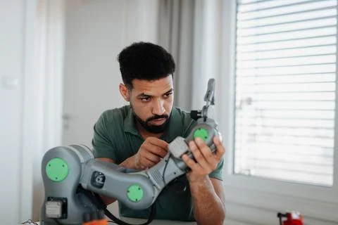 Young engineer building and programming a robotic arm at home. Foto stock