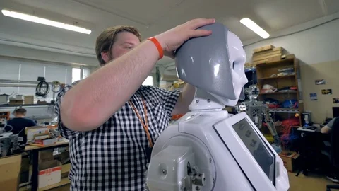 A young engineer checks how robots plastic hair fit. Stock Footage