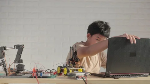Young Engineer Connecting Robot to Laptop for Coding and Testing Stock Footage 307389445