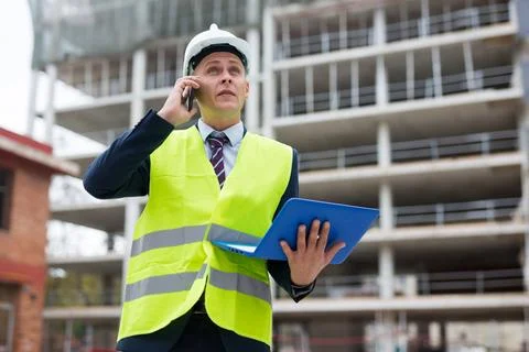 Young engineer, controlling the progress of work on a laptop, talking on a Stock Photos