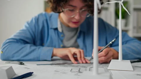 Young engineer designs renewable energy project with wind turbine models in Stock Footage 323716975
