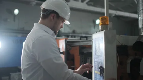 Young engineer in helmet controls the process on the factory Stock Footage 107411816