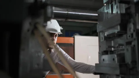 Young engineer in helmet controls the process on the factory Stock Footage 107414108
