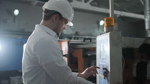 Young engineer in helmet controls the process on the factory Stock Footage 114503858