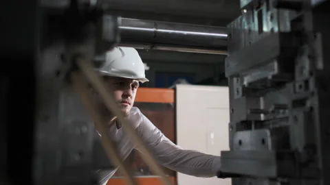 Young engineer in helmet controls the process on the factory Video stock 114505137