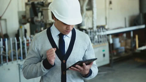 Young engineer in helmet works with table on the factory. 4K 動画素材 91884604