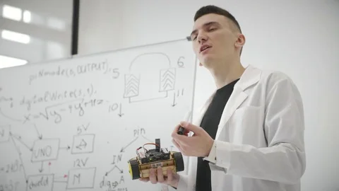 Young engineer holding in hand technician invention and showing on white board Stock Footage 83873500