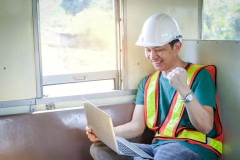 The young engineer holds a notebook computer sitting on a moving train. Stock Photos