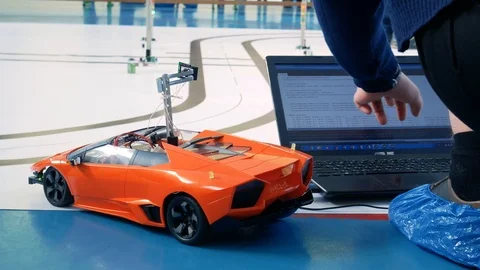 The young engineer makes adjustments to the program code of the robotic vehicle Stock Footage 103540472