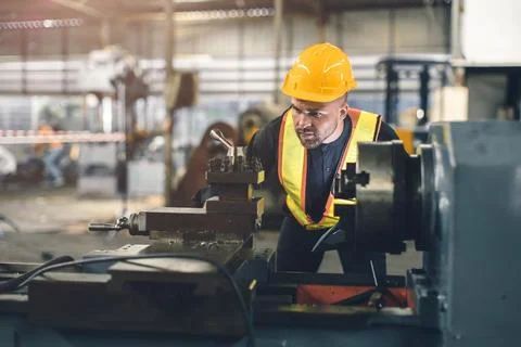 Young engineer male worker work in heavy metal industry CNC lathe machine w.. Foto stock
