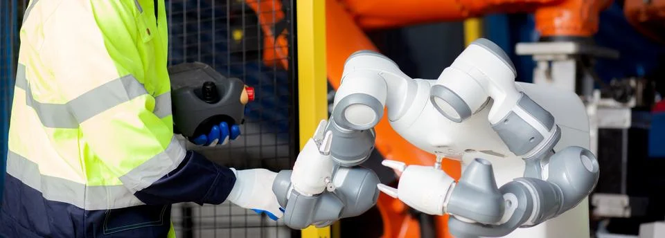 Young engineer man checking and maintenance machine robot arms technology i.. Stock Photos