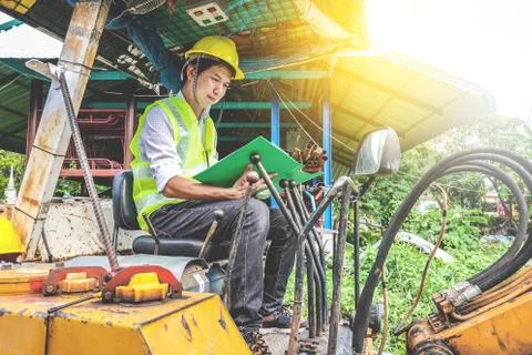 Young  engineer man Hold the file and inspect the document in excavator Stock Photos
