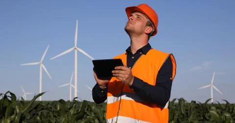 Young Engineer Man Using Digital Tablet Look Up at Wind Turbines Observing Tower 스톡 사진