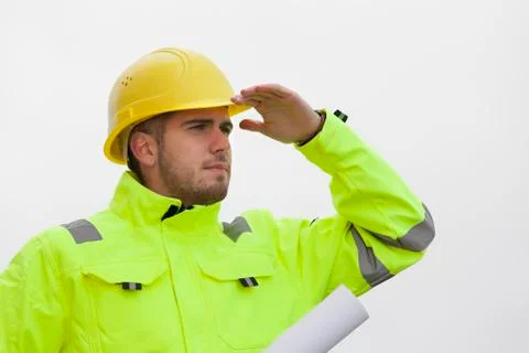 Young engineer or architect in green protective clothing looking out for a su Stock Photos