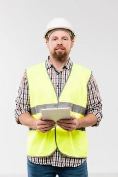Young engineer or foreman in protective helmet and workwear using digital tablet Stock Photos